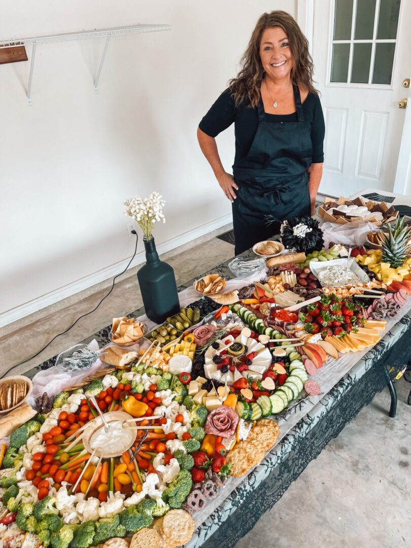 A woman standing next to a table with many different types of food.